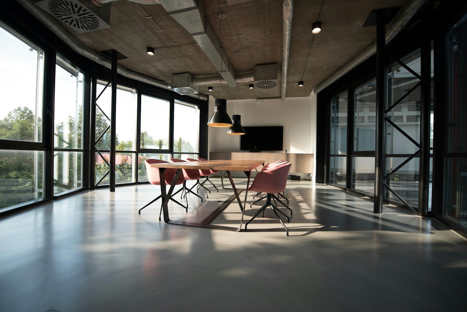 Long conference table in a Casagrand commercial workspace with yellow chairs and hanging plants